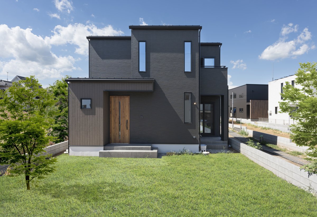 ブラックを基調にしたスクエア型の外観。木目調の玄関ドアがアクセントに。