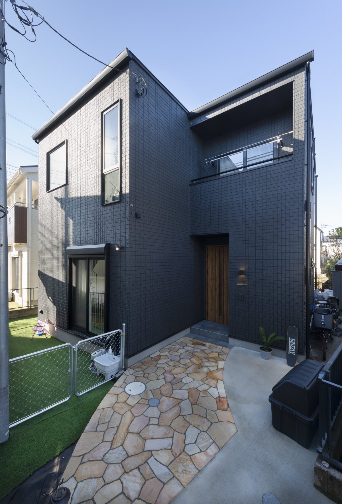 ブラックで統一されたBox型の外観。木目調の玄関ドアがアクセントに。