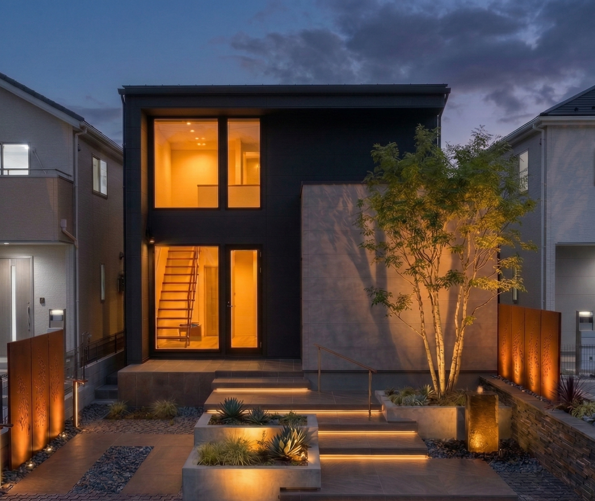 ブラック×グレーのスクエア型の外観。広くとった玄関ポーチではバーベキュー。